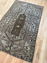 Load image into Gallery viewer, Vintage Anatolian Milas rug 4’2” x 6’11” — angled view of geometric field and dark central medallion